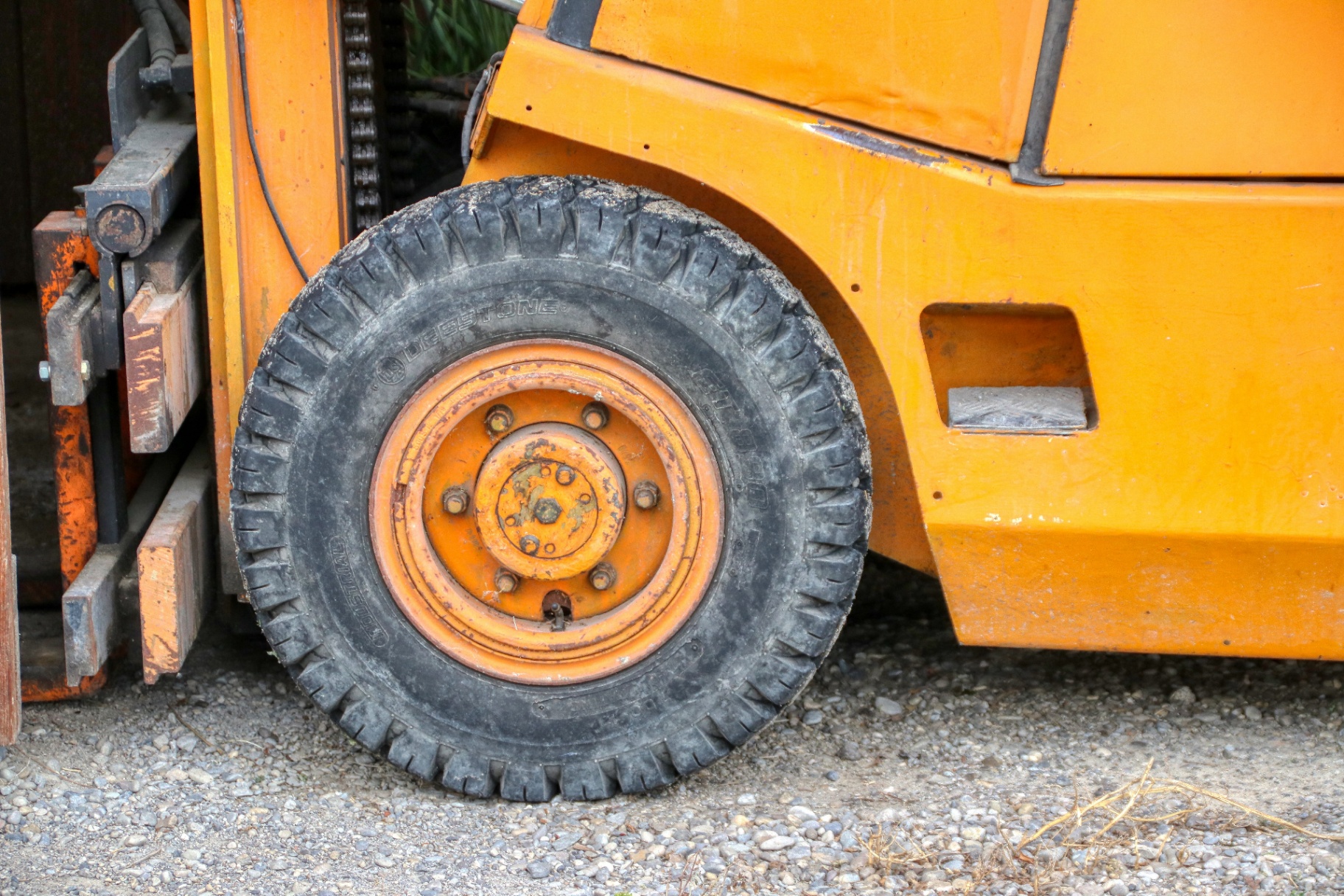 Close-up of a heavy-duty forklift tire mounted on an orange forklift